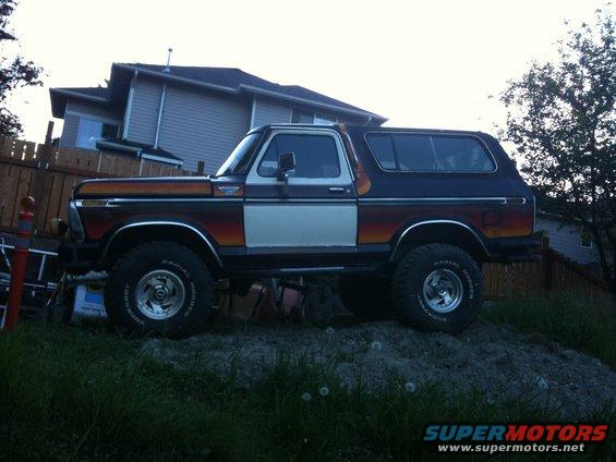 1979 Ford Bronco parked on a dirt mound, side view. Two-tone paint with orange and white