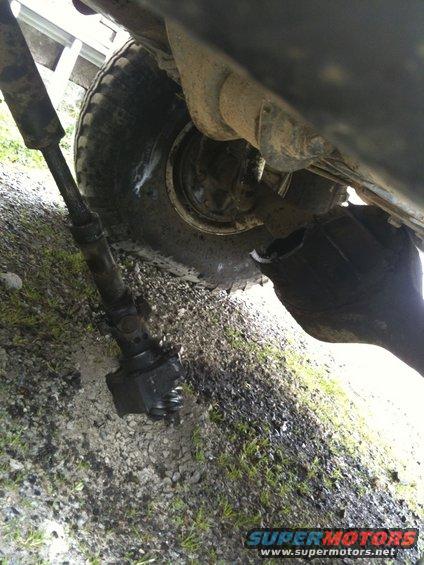 Underside of a vehicle showing a detached driveshaft and differential housing