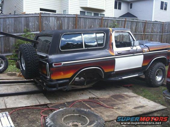 Ford Bronco with custom sunset-style paint, spare tire mounted on rear, being worked on outdoors