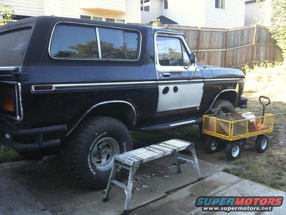 Side view of a black 1979 Ford Bronco with a two-tone door and chrome trim