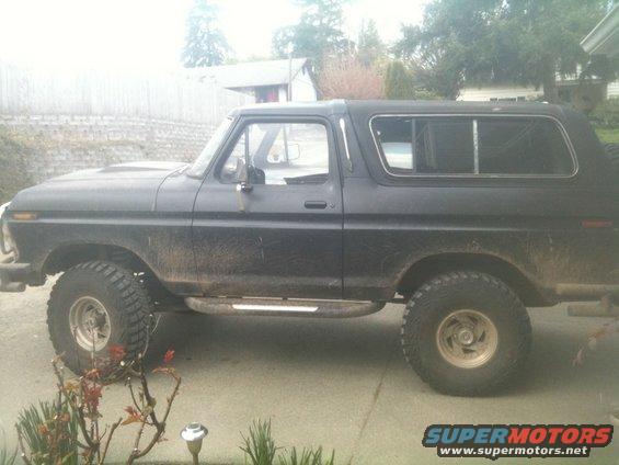 Black 1978 Ford Bronco with side steps and off-road tires, parked on a driveway