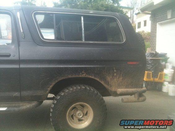 Side view of a black 1979 Ford Bronco with a camper shell