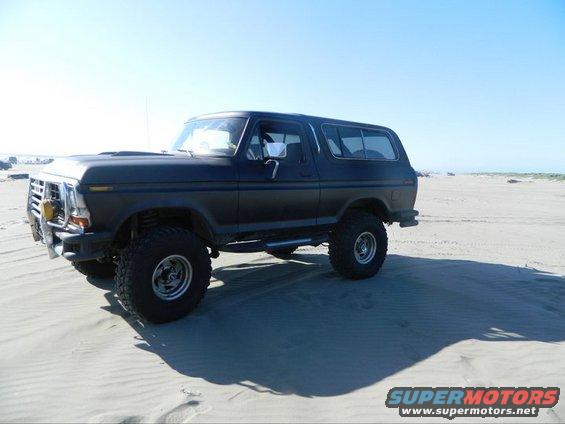 Black Ford Bronco on sand dunes, lifted suspension, aftermarket bumper, side view