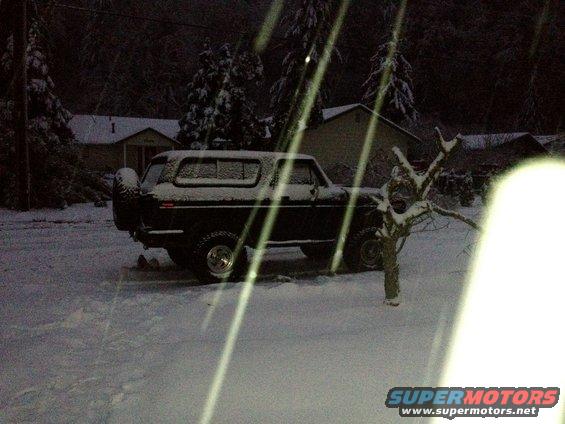 Black Ford Bronco parked in snow, spare tire on back