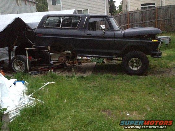 Black Ford Bronco with hood open, lifted for repairs. Suspension components are visible