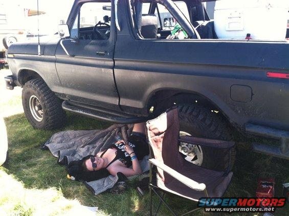 Side view of a black 1979 Ford Bronco with a person underneath