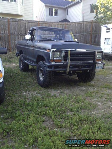 Dark blue Ford F-Series truck with a brush guard and lifted suspension parked on grass