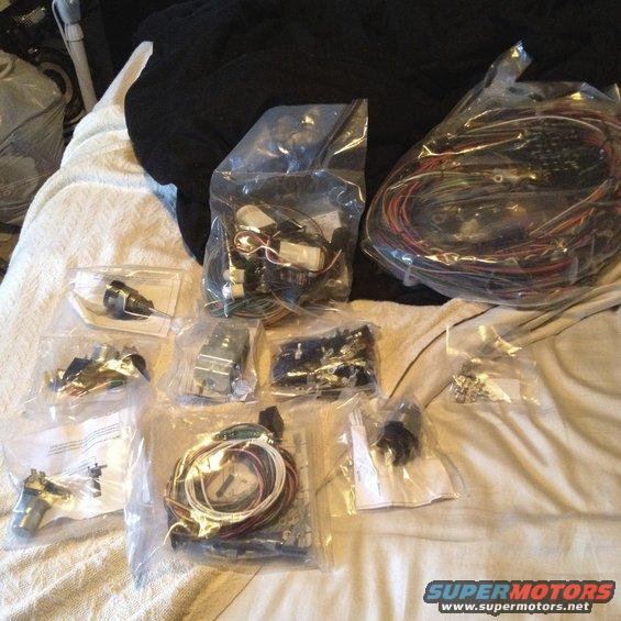 Several plastic bags containing electrical wiring harnesses and components laid out on a white blanket