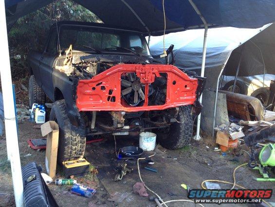 Black Ford Bronco with front end disassembled and red grille support. Tires are large and knobby