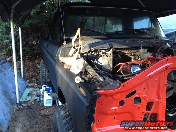1979 Ford truck with hood open, engine exposed, front fender removed for repair. Red painted inner fender visible