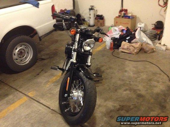 Black motorcycle parked next to a white pickup truck in a garage