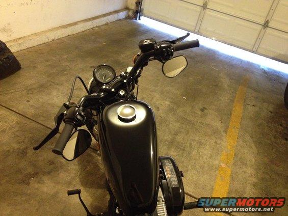 Black motorcycle handlebars and fuel tank, viewed from above