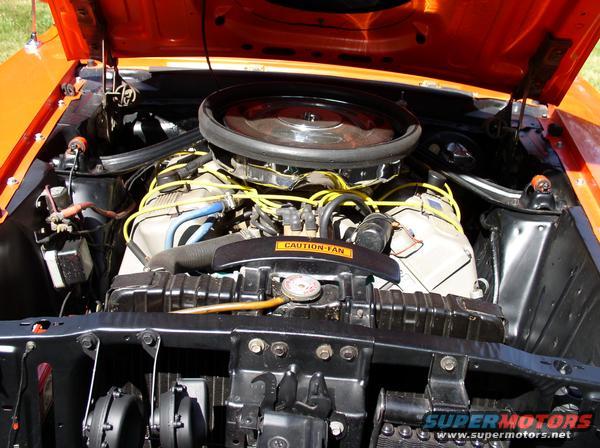 Orange car engine bay with yellow spark plug wires and a 'Caution-Fan' sticker