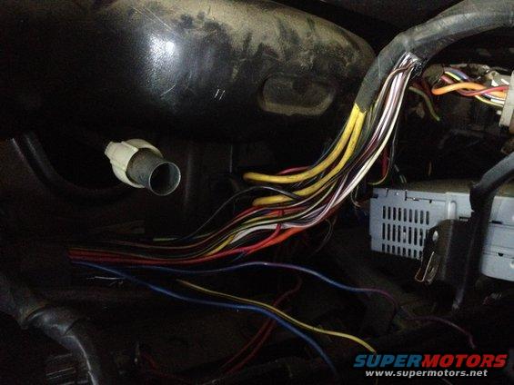 Bundle of colorful wires and a car stereo unit are visible in a dark vehicle interior