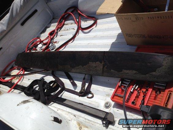 Truck bed with a dark, segmented object, red jumper cables, and a red toolbox with sockets