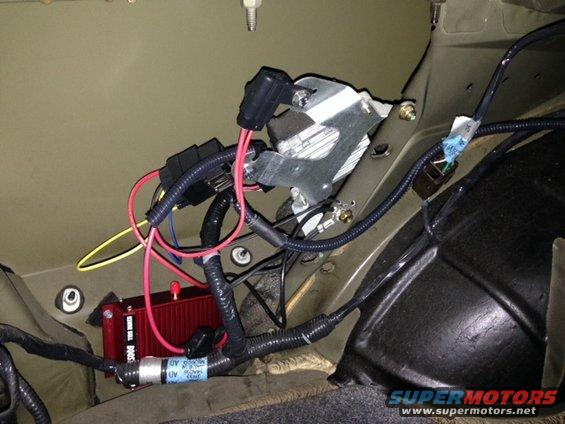 Red electronic module with wiring and a silver bracket with a fuse box