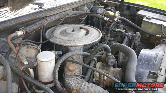 Engine bay with air cleaner, hoses, and radiator fan visible. Text 'CAUTION' on fan shroud