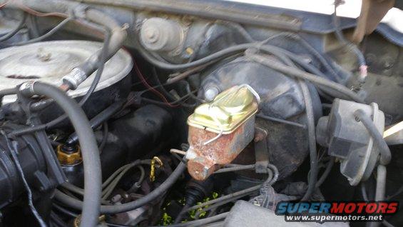 Engine bay with brake master cylinder, air filter housing, and various hoses and wires