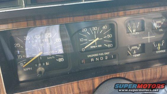 Dashboard with speedometer, tachometer, fuel, oil, temp, and charge gauges. Wood grain trim visible