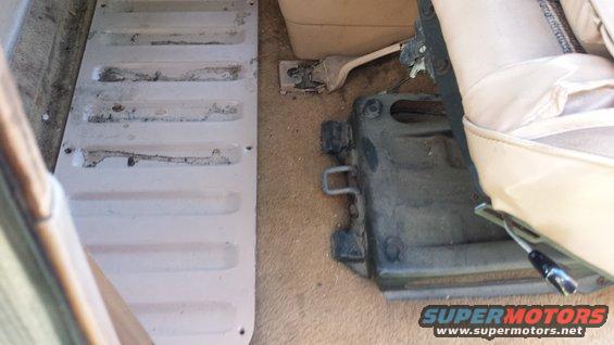 Interior view of vehicle floor with a ribbed metal panel and seat mounting hardware