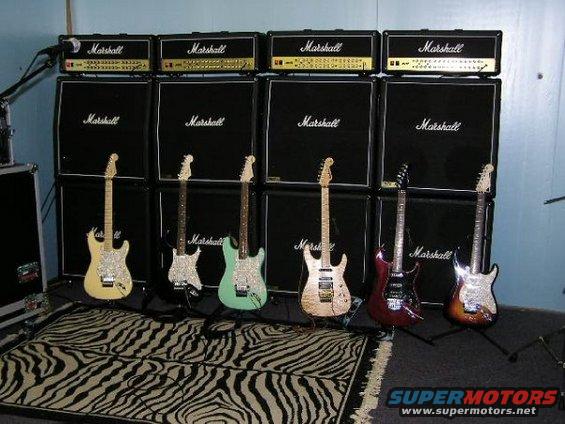 Electric guitars lined up in front of Marshall amplifiers with a zebra-print rug