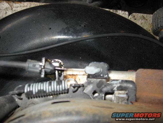Throttle cable mechanism with spring and metal bracket, close-up view