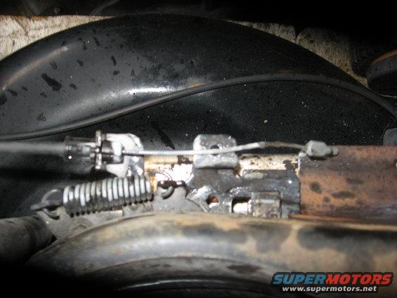Close-up of a throttle cable mechanism with a spring and metal bracket