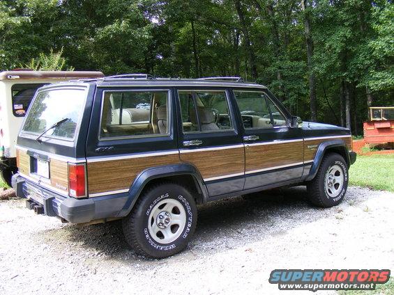 Dark blue Jeep Cherokee with wood paneling, rear 3/4 view