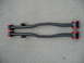 1993 Mazda MX-3 - A pair of black trailing arms with red bushings are shown laid out on a concrete surface.