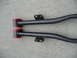 1993 Mazda MX-3 - Two black control arms with red bushings are shown laid out on a concrete surface.