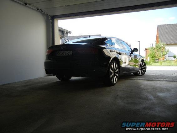 Black Audi sedan parked in a garage, rear view. License plate reads PB-WG 2030