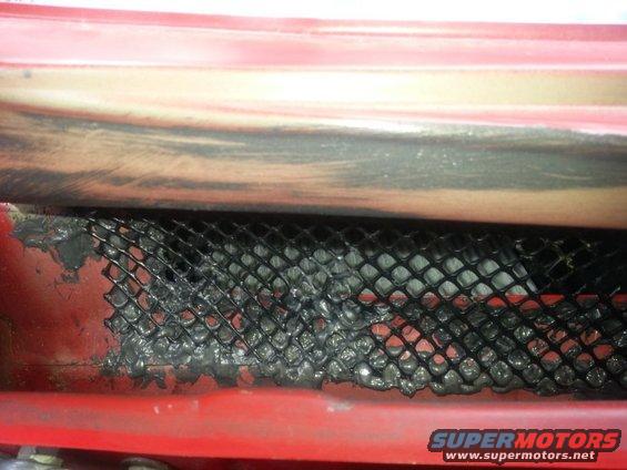Red painted metal housing with black mesh covering, sealed with grey putty