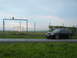 2003 Audi A6 - A dark Audi A6 Avant wagon sits parked next to a chain-link fence with airport runway lights in the background.