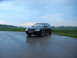 2003 Audi A6 - A dark Audi A6 Avant is parked on a wet road under a cloudy sky.