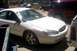 2000 Ford Taurus - A white 2000 Ford Taurus sedan with visible damage sits in a junkyard next to other vehicles.