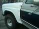 1986 Ford Bronco - The front fender and door of a 1986 Ford Bronco, showing its two-tone paint scheme and chrome accents.