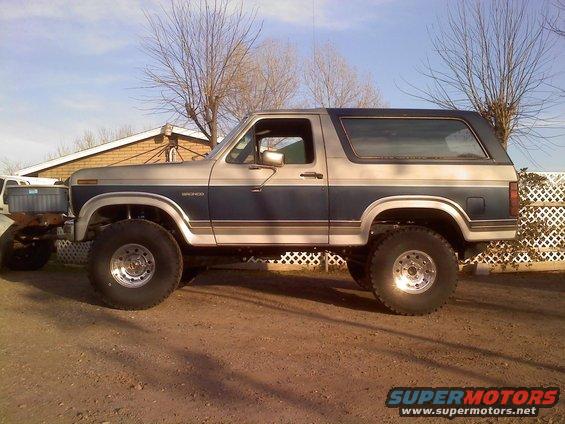 Lifted Ford Bronco with blue and silver two-tone paint, sitting on large off-road tires