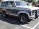 1986 Ford Bronco - This Ford Bronco features a two-tone paint scheme with a dark blue stripe separating the gray upper and lower body panels.