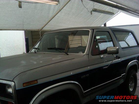 Front 3/4 view of a two-tone gray and blue 1986 Ford Bronco parked indoors