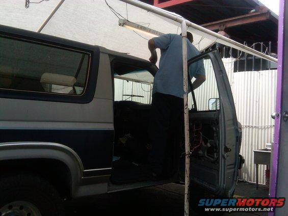 Man working on the interior of a 1986 Ford Bronco with the driver's door open