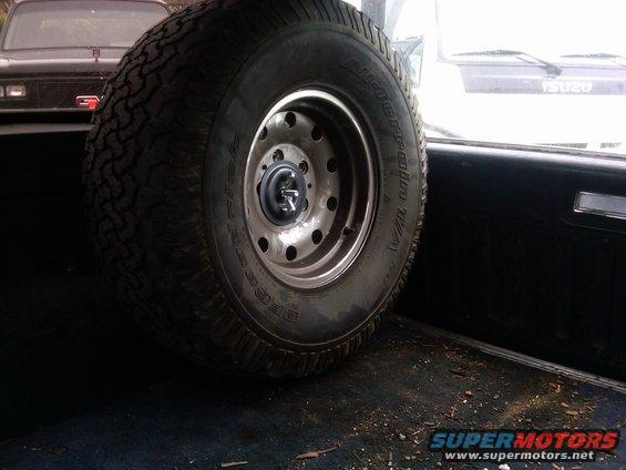 Spare tire mounted inside a vehicle, with another vehicle visible in the background