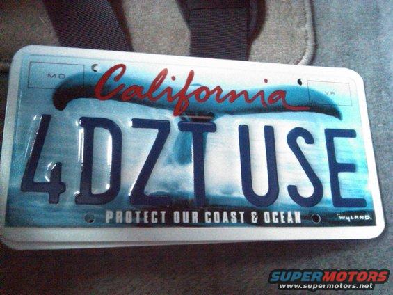 California license plate with whale tail graphic and text '4DZ T USE PROTECT OUR COAST & OCEAN'