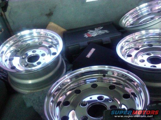 Four chrome wheels stacked in a vehicle's cargo area