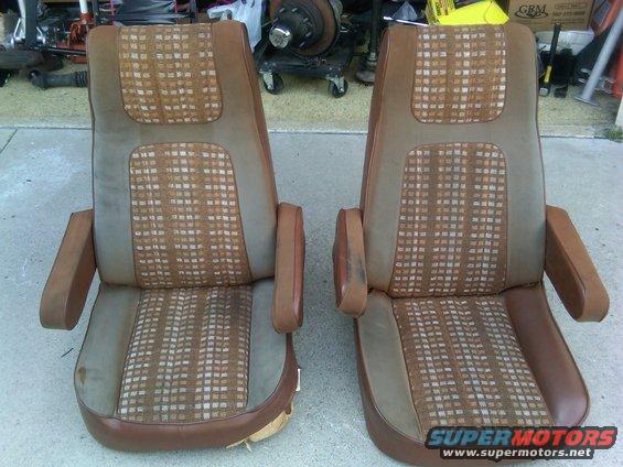 Two brown and tan plaid bucket seats with armrests, showing some wear