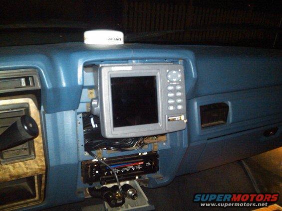 Blue dashboard interior with a mounted GPS unit and an aftermarket radio below it. A white 'LOWRANCE' antenna is on top