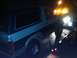 1986 Ford Bronco - A Ford Bronco is loaded onto a tow truck under the glow of emergency lights.