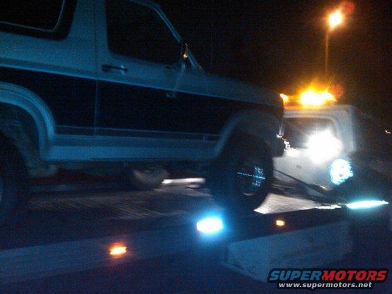 1986 Ford Bronco on tow truck at night
