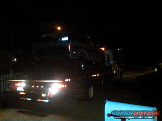 tow truck carrying a dark-colored SUV at night