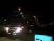 1986 Ford Bronco - A tow truck transports a vehicle at night, illuminated by its own lights and a distant streetlamp.