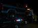 1986 Ford Bronco - A Ford Bronco is transported on a tow truck at night, showing its side profile and taillight detail.